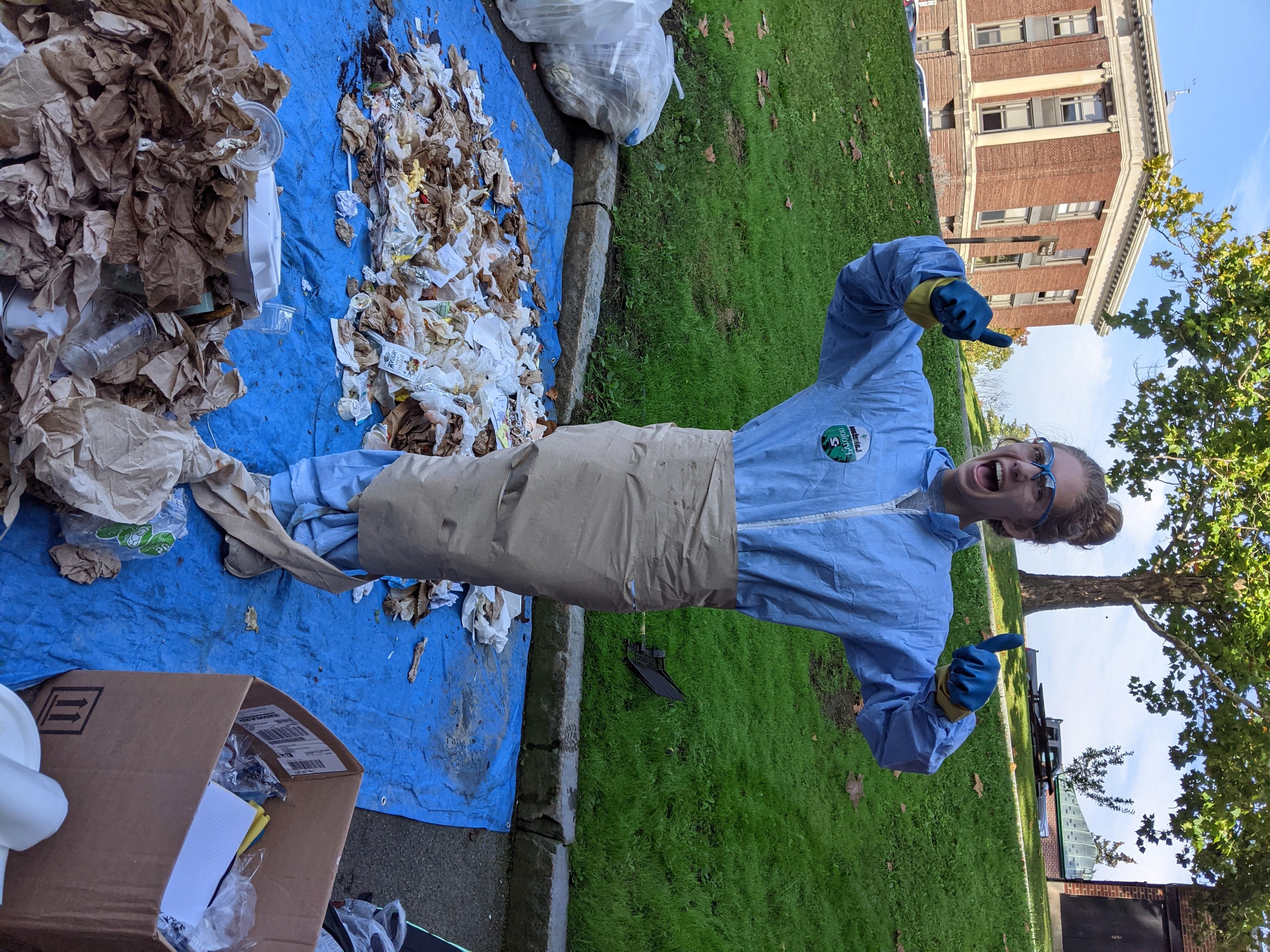 Club member wrapped in paper towels while conducting waste audit. Smiling, giving thumbs up