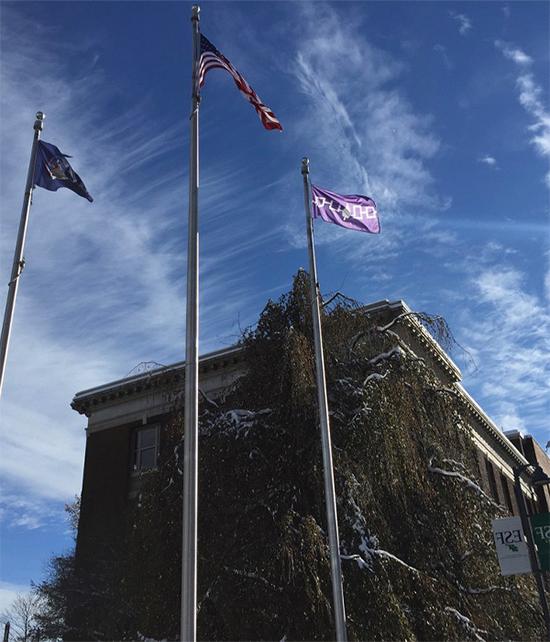 3 flags beside the Bray Hall at E SF. From left to right, flag of the Haudenosaunee nation, United States of America, and the New York State