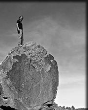 black and white image of raymond gutteriez standing on a rock