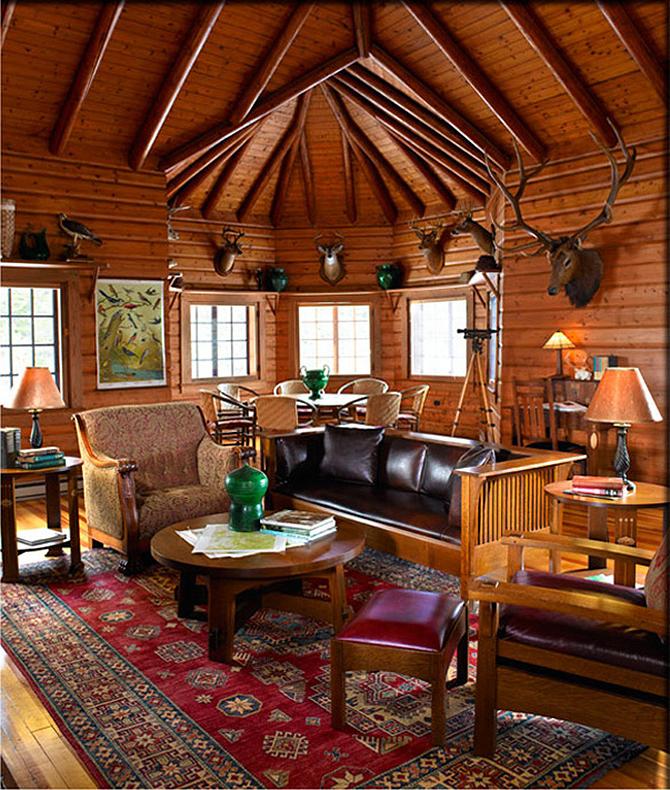杨梅休息室内室. 墙上有鹿头. 有一些图案的红地毯, 一张沙发，两边各有扶手椅，中间有一张圆形咖啡桌